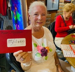A bingo winner holding up an envelope with a gift certificate for a restaurant