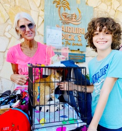 A smiling boy visiting a kitty at the PuRR Project Table with a volunteer