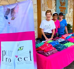 Volunteers posing at the PuRR table with all the bright colored items for sale