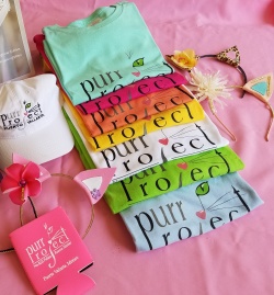 colorful purr project t-shirts folded on a table 