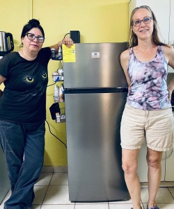 Two womens posing by a silver refrigerator