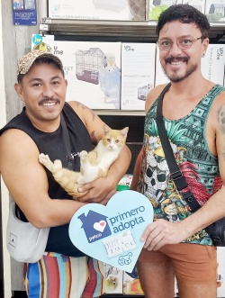 Two men who adopted Woody are posing with him 