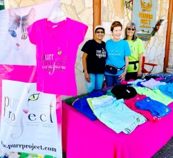 PuRR volunteers standing at the PuRR Project table with items to sell.